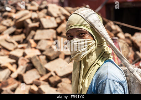 earthquake reconstruction worker in Kathmandu wearing a dust mask and carrying a sack of rubble Stock Photo