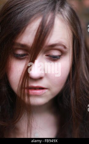 Portrait of a young woman with eyes cast down and hair falling on her face Stock Photo