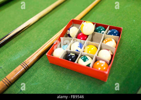 pool balls and cues on a pool table at a community centre in England Stock Photo