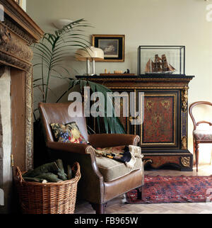 Brown leather armchair and antique painted cabinet in Victorian style living room Stock Photo