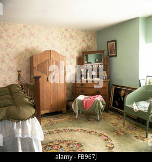 Floral carpet in forties bedroom with a wooden wardrobe and floral wallpaper Stock Photo