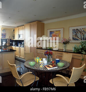 Wicker+metal chairs at circular tile topped table in a townhouse apartment kitchen Stock Photo