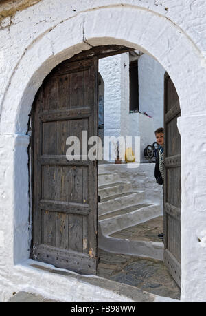 A boy looks through the half open traditional wooden door of his house on April 12, 2015 in Berat, Albania. Stock Photo