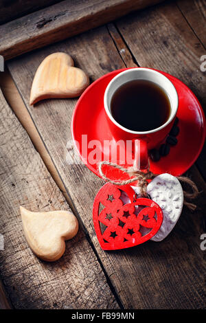 Red Cup with black coffee and two carved decorative wooden heart.Selective focus Stock Photo