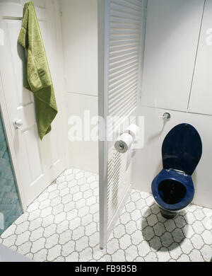 Blue toilet and louvre room divider in seventies bathroom with white tiled floor Stock Photo