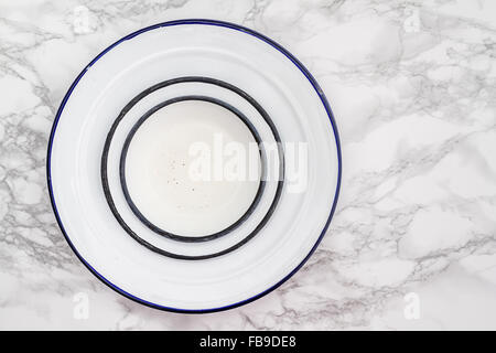 Empty white vintage enamel plates on white marble background Stock Photo