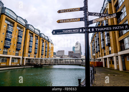 View of Canary Wharf from thames path against a direction board. Stock Photo