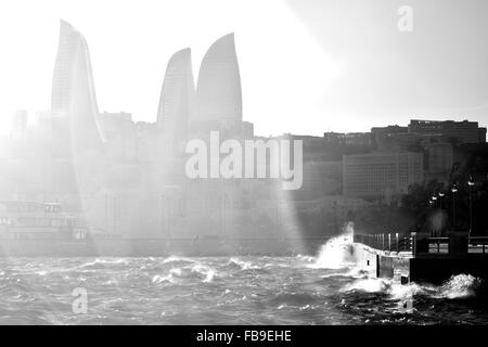 Stormy Caspian Sea with waves breaking against the Bulvar. Flare over Flame Towers in Baku, capital of Azerbaijan