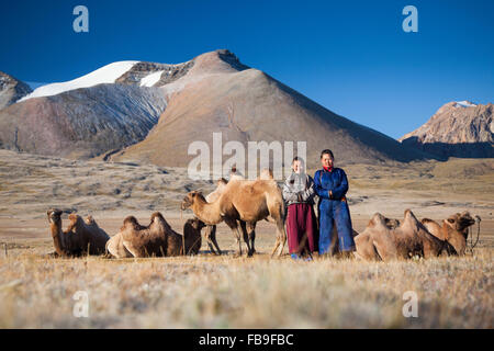 Trek guides pose amongst pack camels on a frosty morning in the remote Kharkhiraa Turgen National Park in far-western Mongolia. Stock Photo