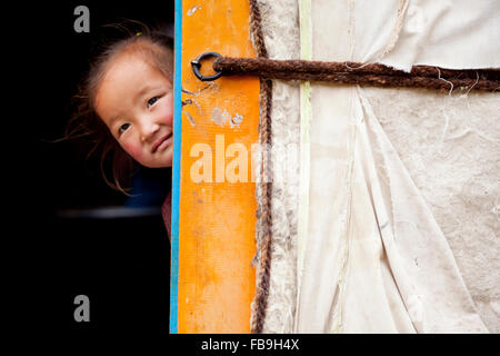 A cheeky young girl pokes her head out from inside her family's ger in Kharkhiraa Turgen National Park, Mongolia. Stock Photo