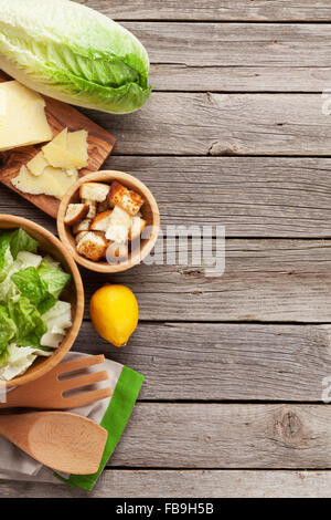 Fresh healthy caesar salad cooking on wooden table. Top view with copy space Stock Photo