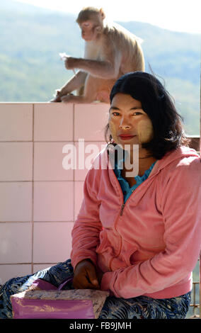 A Burmese pilgrim and a monkey on top of Taung Kalat near Mt. Popa in Myanmar. Stock Photo