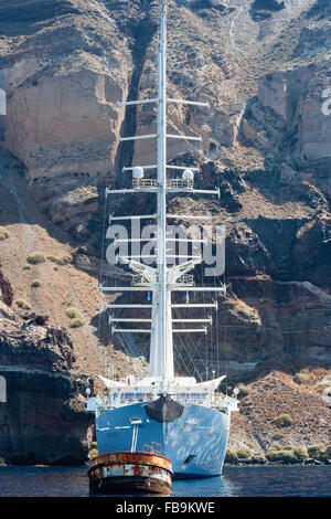 Santorini in Aegean sea. Ocean-going luxury four-masted yacht, 'wind spirit', operated by Windstar Cruises, moored under towering cliffs. Facing, bows. Stock Photo