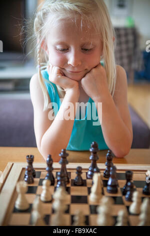 Sweden, Vastergotland, Lerum, Girl (8-9) playing chess in living room Stock Photo