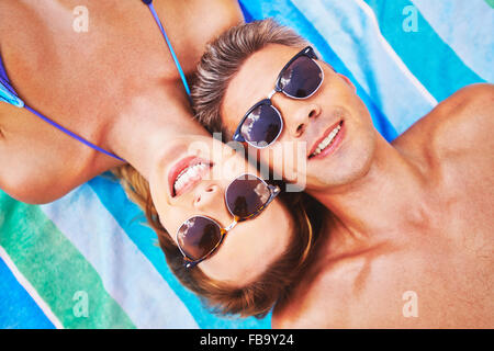 Portrait of a young attractive couple sunbathing and wearing sunglasses Stock Photo