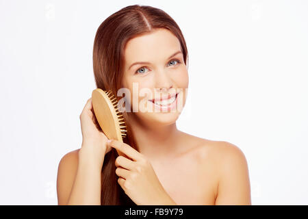 Attractive smiling woman combing her hair Stock Photo