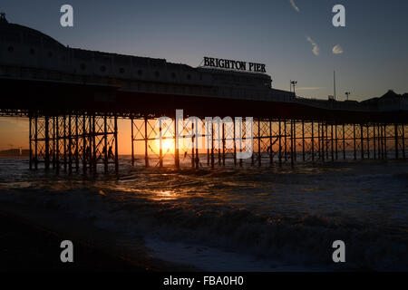 Brighton Pier is silhouetted against a beautiful sunrise on the beach in Brighton, East Sussex, UK. Stock Photo