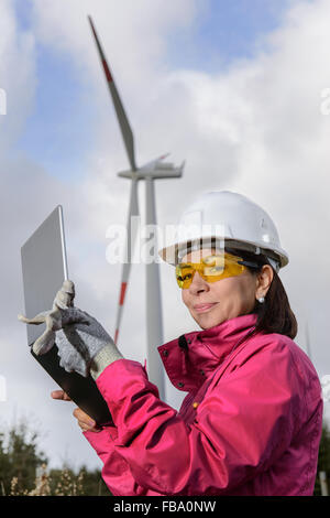 Engineer woman checking production, with laptops, wind turbines on the site. Stock Photo