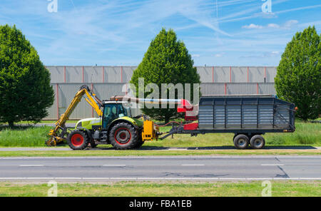 tractor mowing grass along a road Stock Photo