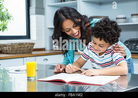 Kind mother helping her son doing homework Stock Photo