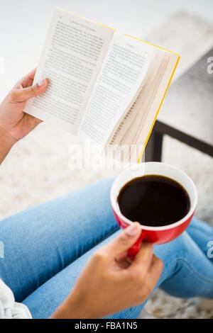 Cropped image of woman with coffee reading book Stock Photo