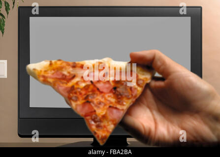 Man hand with pizza slice watching TV copy space Stock Photo