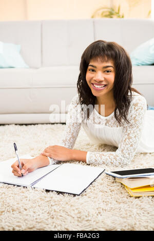 Smiling woman writing notes while looking the camera Stock Photo