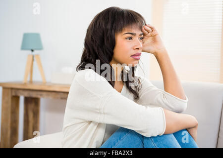 Stressed woman holding her head on couch Stock Photo