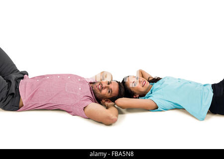 Smiling couple laying on floor with hands on their heads Stock Photo