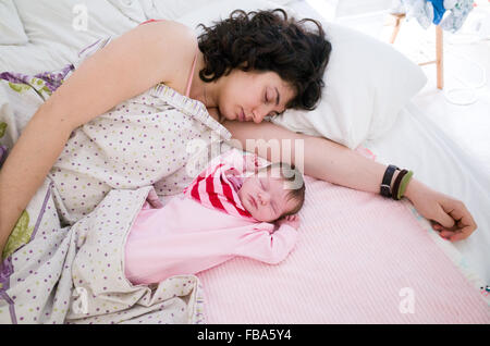 Mother sleeping with her newborn baby beside her in same bed Stock Photo