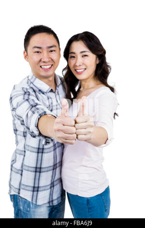 Happy couple showing thumbs up against white background Stock Photo