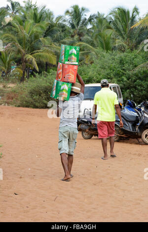 A young Indian boy carries supplies of beer to a beach cafe on Candolim Beach in North Goa, India Stock Photo