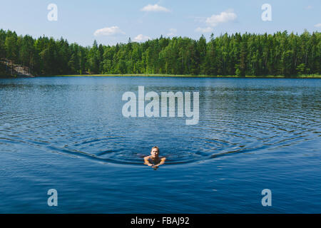 Finland, Uusimaa, Espoo, Lake Kvarntrask, Young man swimming in lake