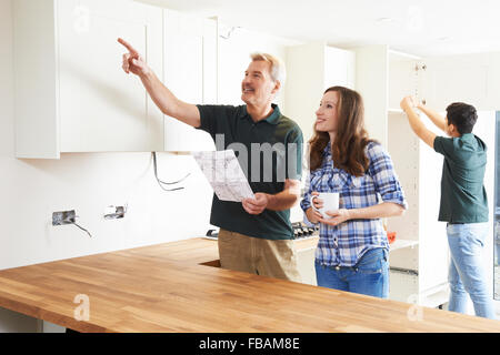 Woman With Carpenter Looking At Plans For New Kitchen Stock Photo