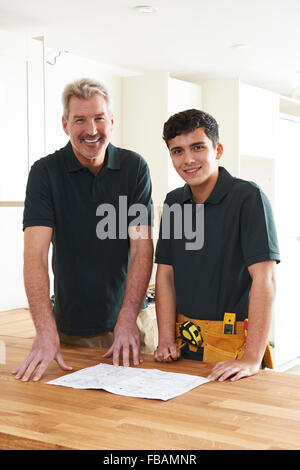 Carpenter And Apprentice Installing Luxury Fitted Kitchen Stock Photo
