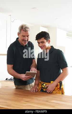 Carpenter And Apprentice With Digital Tablet Fitting Luxury Kitchen Stock Photo