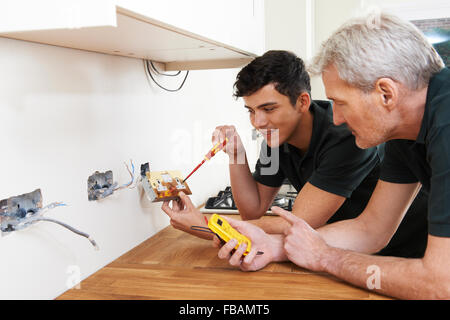 Electrician With Apprentice Working In New Home Stock Photo