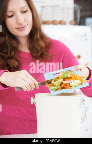 Woman Scraping Vegetable Peelings Into Recycling Bin Stock Photo