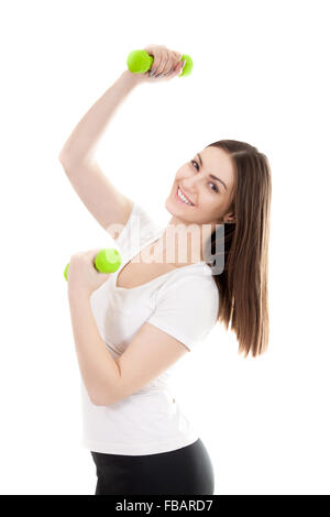 Young smiling woman in white t-shirt trains biceps lifting green colored dumbbell weights, workout, doing fitness exercises. Iso Stock Photo