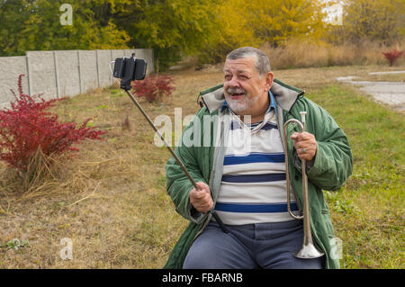 Outdoor portrait of  senior man smiling while doing selfie outdoor for online social networking service Stock Photo