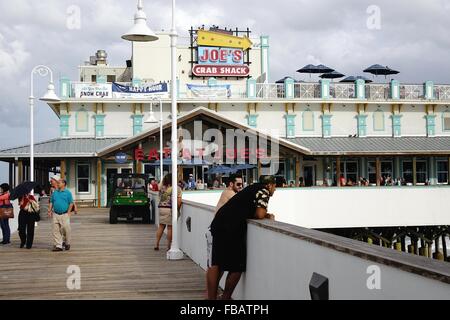 People on a pedestrian walkway leading to joe's crab shack 'eat at Joe's' on the Daytona Beach boardwalk Stock Photo