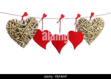 Three red and two wicker valentine hearts hanging from a red string line isolated on white background Stock Photo