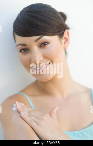 Portrait of a dark-haired young woman applying body lotion Stock Photo