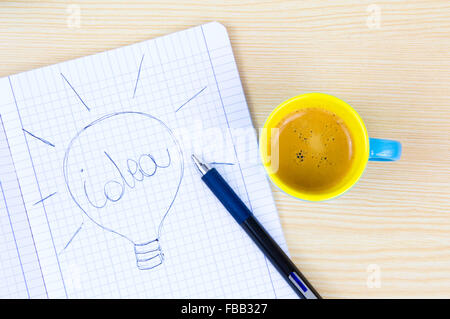 Colorful coffee cup with draw of bulb on paper on wood table Stock Photo