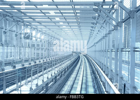 Tokyo monorail transportation system line in metal tunnel cage. Blue toned Stock Photo