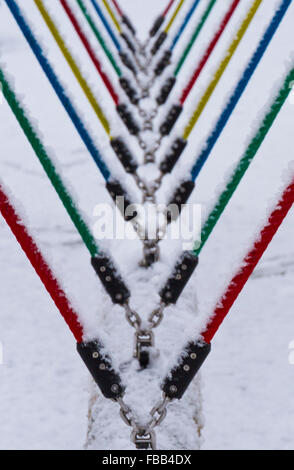 snow covered swing with multi coloured ropes in Calder Park, Scotland Stock Photo
