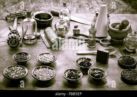 Nature's Pharmacy. Vintage mortar and pestle surrounded by various herbs, ingredients and tonics. Stock Photo