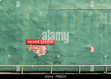 Red private parking sign on an old green wall in Wallace, Idaho Stock Photo