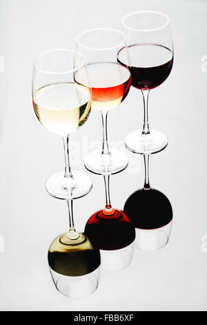Three Glasses Filled with White, Rose and Red Wines on an Illuminated Background with Reflections Stock Photo