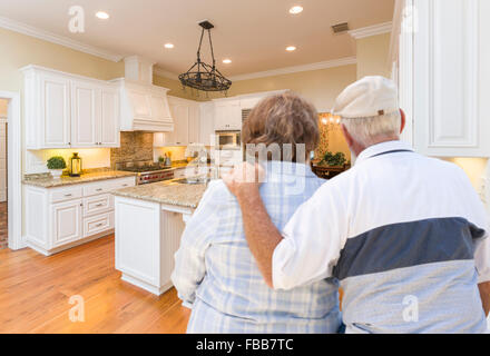 Happy Senior Couple Looking Over Beautiful Custom Kitchen Design. Stock Photo
